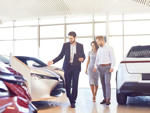 Autokäufer werden von Autoverkäufer durch das Autohaus geführt.