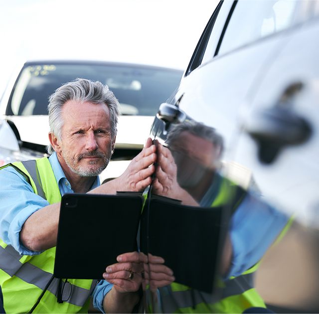 Mann nimmt Auto in Augenschein, um es präzise bewerten zu können.