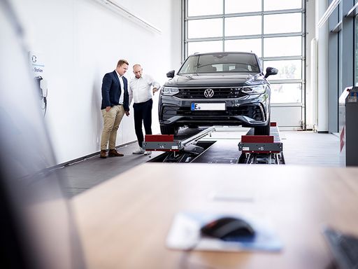 Werkstattkunde und Werkstattmitarbeiter vor einem Kompakt-SUV. DAT Report 2024 Thema des Monats Mai