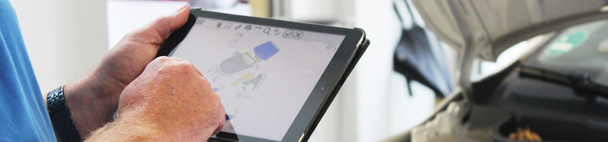 Kfz-Mechatroniker in Werkstatt mit Tablet, auf dem SilverDAT 3 läuft: Schnittstellen zu SilverDAT gibt es in den führenden Software-Programmen für Autohäuser, Werkstätten und Sachverständige