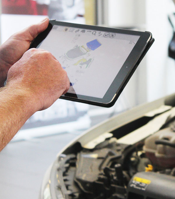Kfz-Mechatroniker in Werkstatt mit Tablet, auf dem SilverDAT 3 läuft: Schnittstellen zu SilverDAT gibt es in den führenden Software-Programmen für Autohäuser, Werkstätten und Sachverständige 