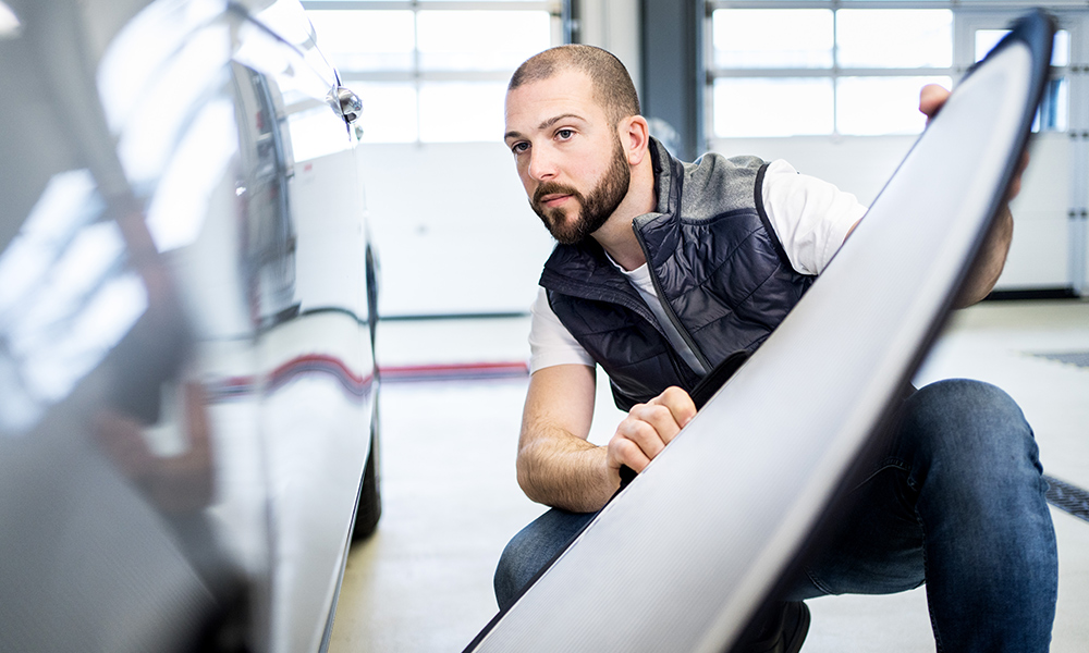 Ein Kfz-Gutachter begutachtet einen Schaden am Fahrzeug und bewertet dieses im Anschluss mit der Sachverständigen-Software SilverDAT 3 Expert Partner