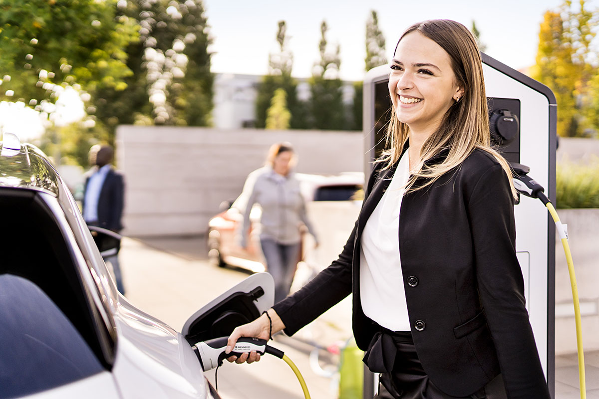 Bild: Frau an AC Ladesäule lädt ein E-Auto