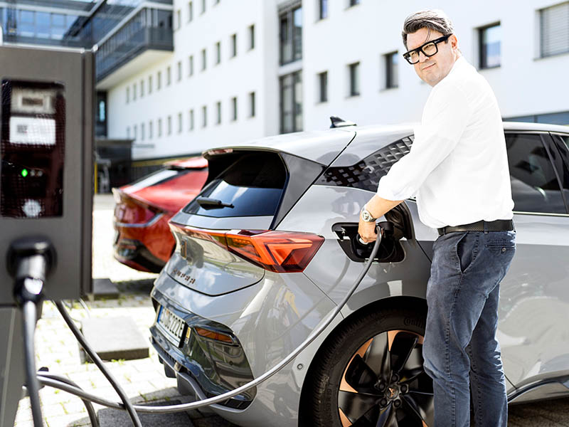 Ein Mann lädt am AC-Lader ein E-Auto (Cupra Born).