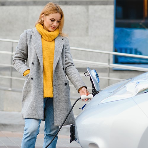 Frau lädt ihr E-Auto. DAT-Report Kapitel 2: Informationen über die Sicht alternativer Antriebe bei Autokäufern