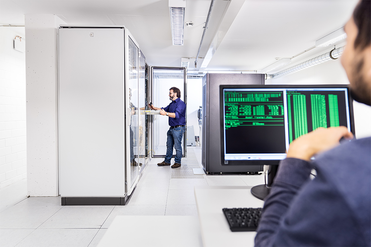 Man sitzt vor Monitor mit grünen Programmierzeilen